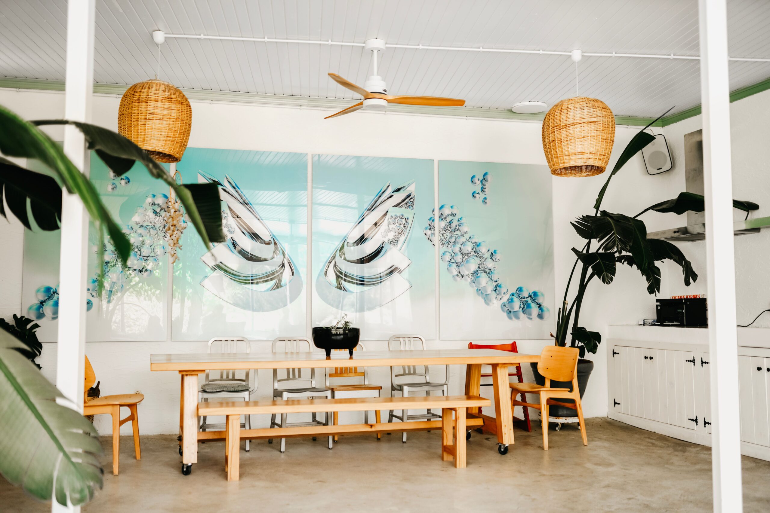 Bright dining space with modern decor, tropical plants, and abstract artwork.